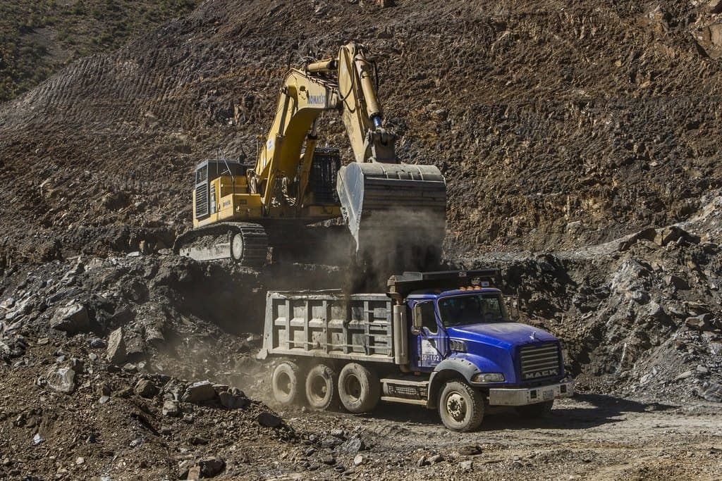 An excavator loading a dump truck at a work site.