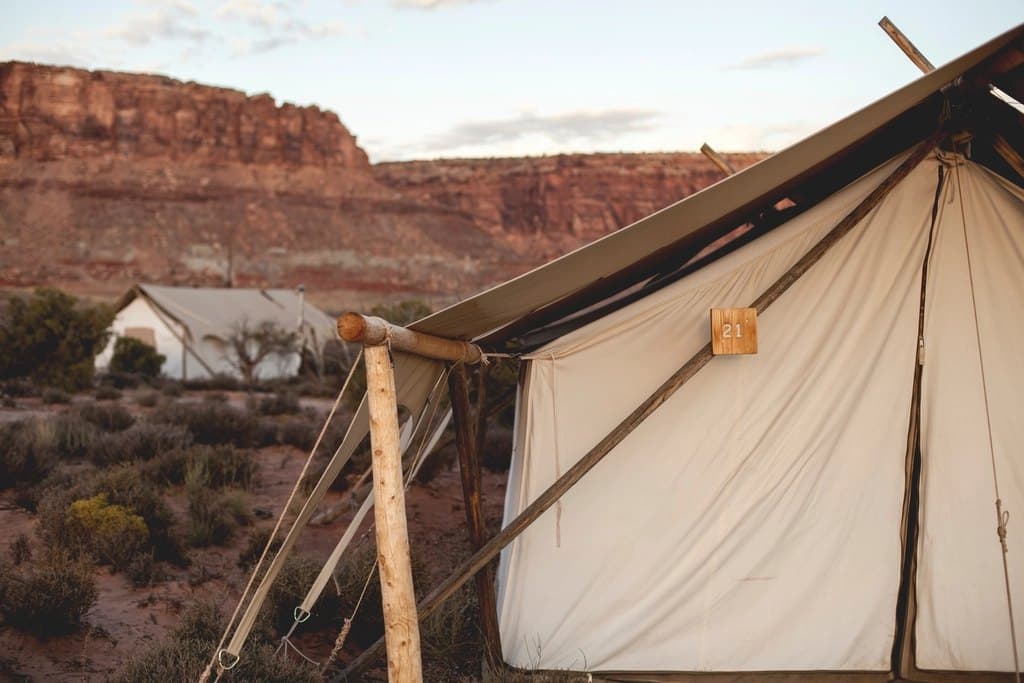 Canvas glamping tents in a desert canyon at sunset.